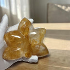 Golden Healer Quartz orchid carving held in gloved hand showing detail