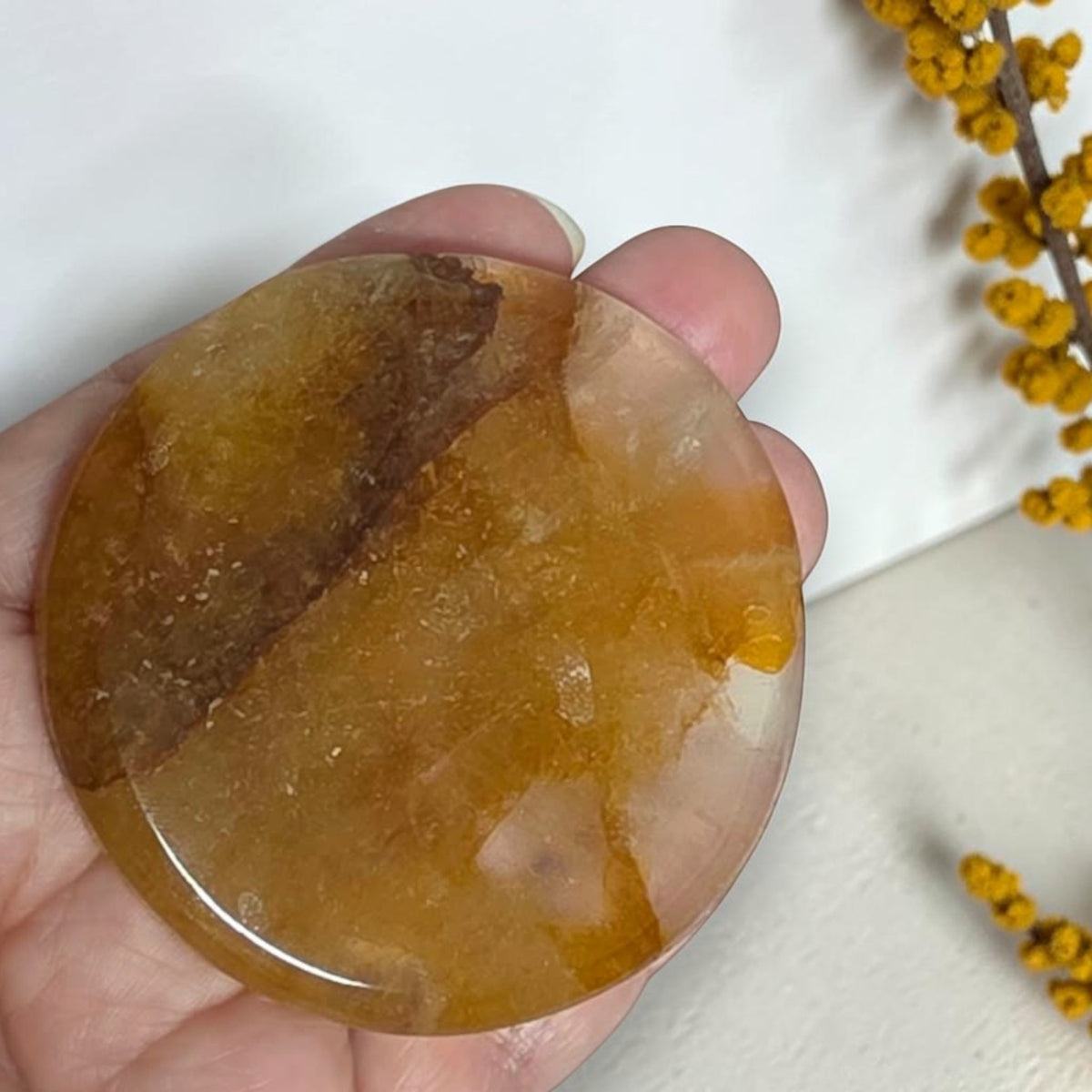 Golden Healer Quartz full moon carving held in a hand