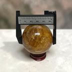 Golden Healer Quartz sphere caliper measurement showing ~55mm diameter