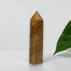 Golden Healer Quartz tower front view with green plant