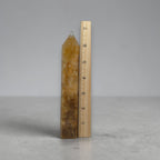 Amber quartz tower with pointed tip, slim shape beside measuring ruler