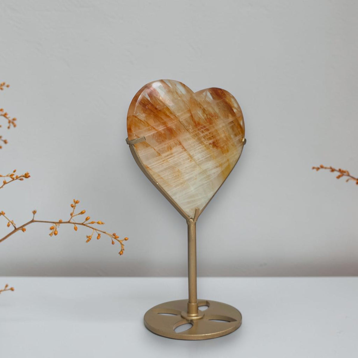 Golden Healer quartz heart displayed on a gold toned stand