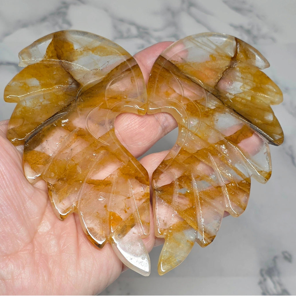 Polished quartz wings with carved feathers and a heart shaped opening