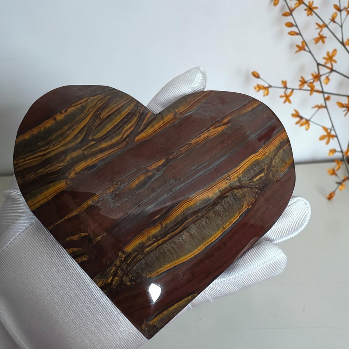 Polished tiger iron heart with golden bands across reddish brown and dark gray tones