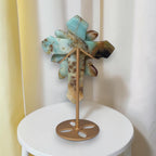 Amazonite crystal cross sculpture with carved roses, viewed from back on stand