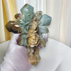 Amazonite crystal cross with carved roses, held by white-gloved hand