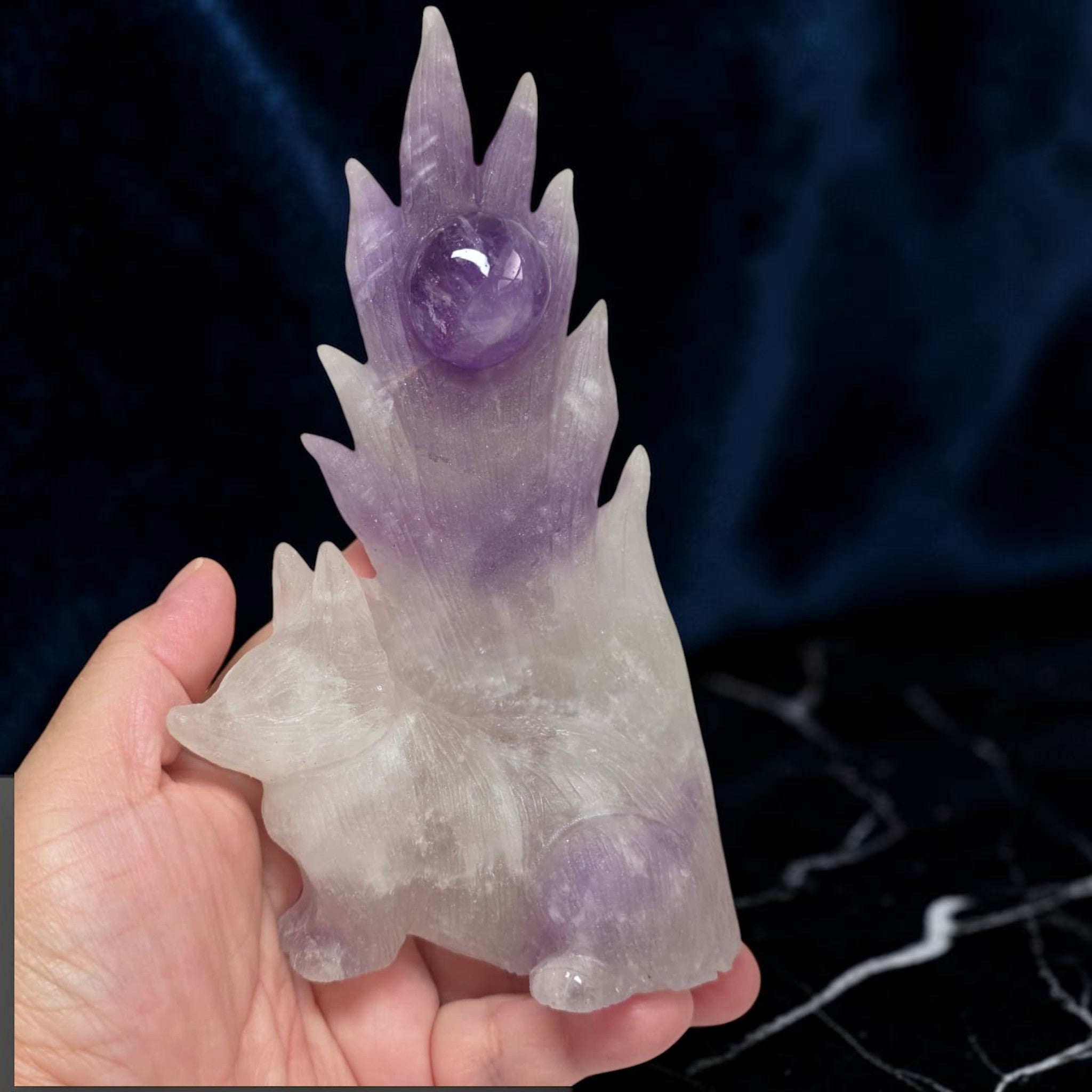 Large amethyst nine-tailed fox carving held in hand showing scale