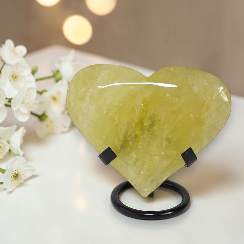 Heart-shaped green stone on a stand with white flowers in the background
