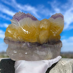 Eagle crystal carving with yellow-and-ivory wings, purple tips, and gray natural base
