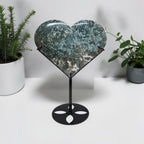 Large green agate heart on stand with plants in background