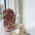 Pink amethyst crystal cluster slab held beside white chair seat cushion