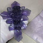 Large purple fluorite cross ornament with carved rose details, close-up in hand