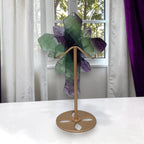 Rainbow fluorite cross sculpture with carved rose details on tall metal stand, upright