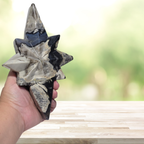 Hand holding star-shaped agate crystal carving, gray and white with dark blue facets