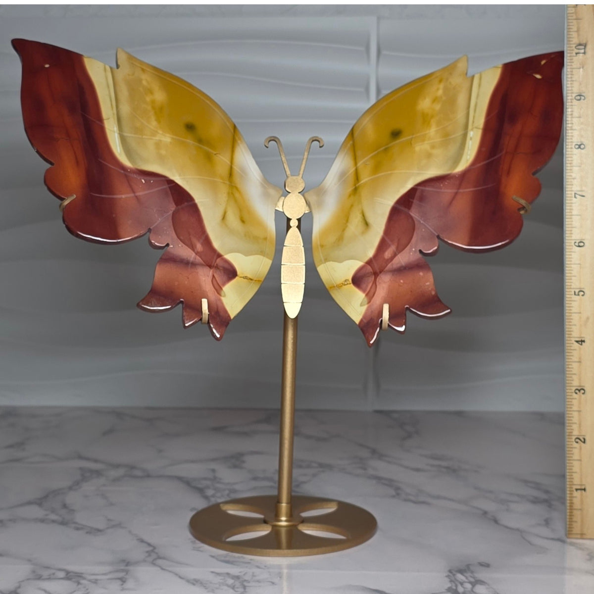Mookaite jasper butterfly displayed with its metal stand beside a ruler