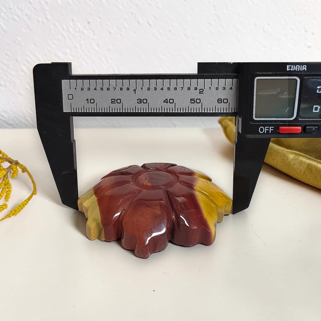 Carved Mookaite Jasper flower shown with measuring tool