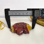 Carved Mookaite Jasper flower shown with measuring tool