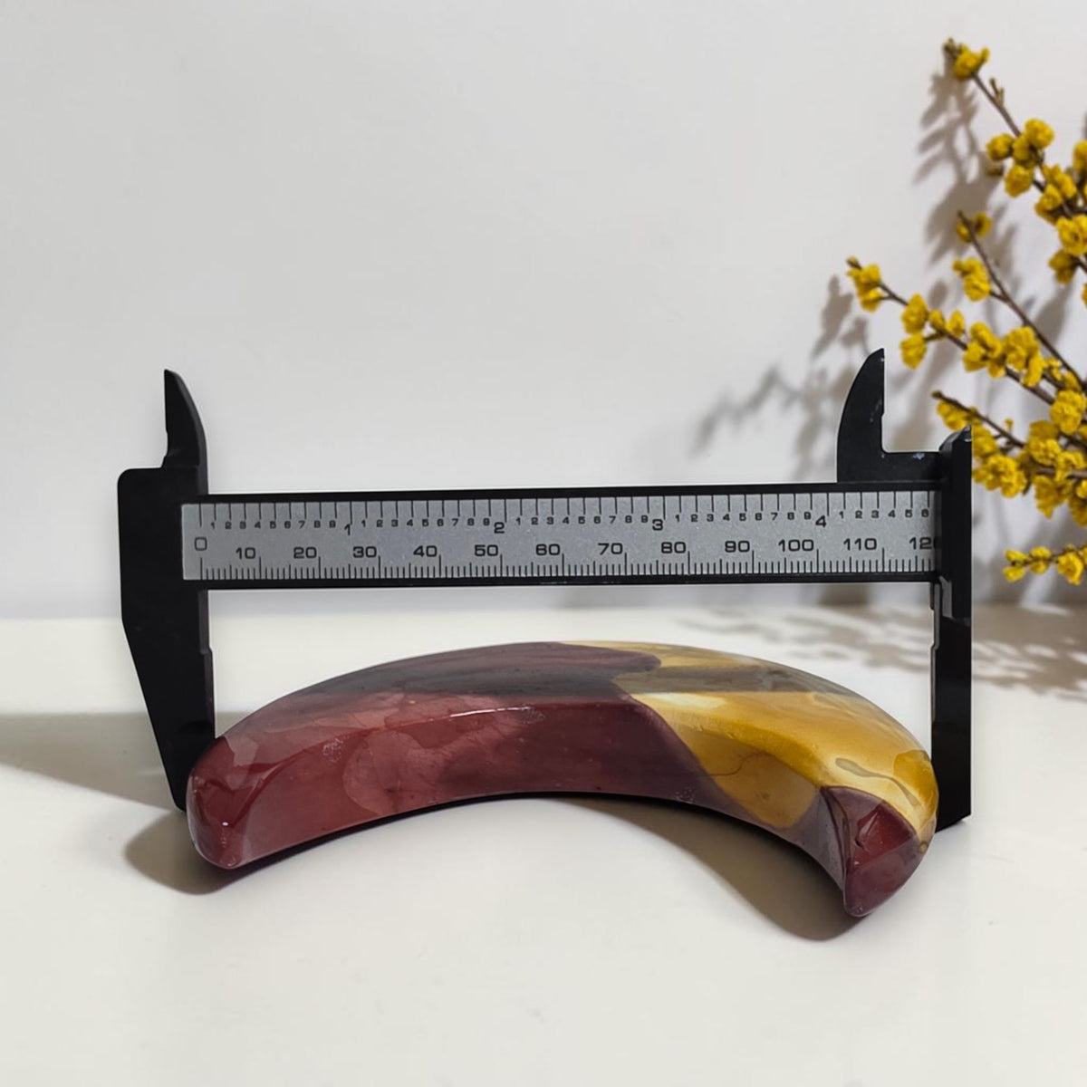 Mookaite Jasper crescent moon shown with measuring tool