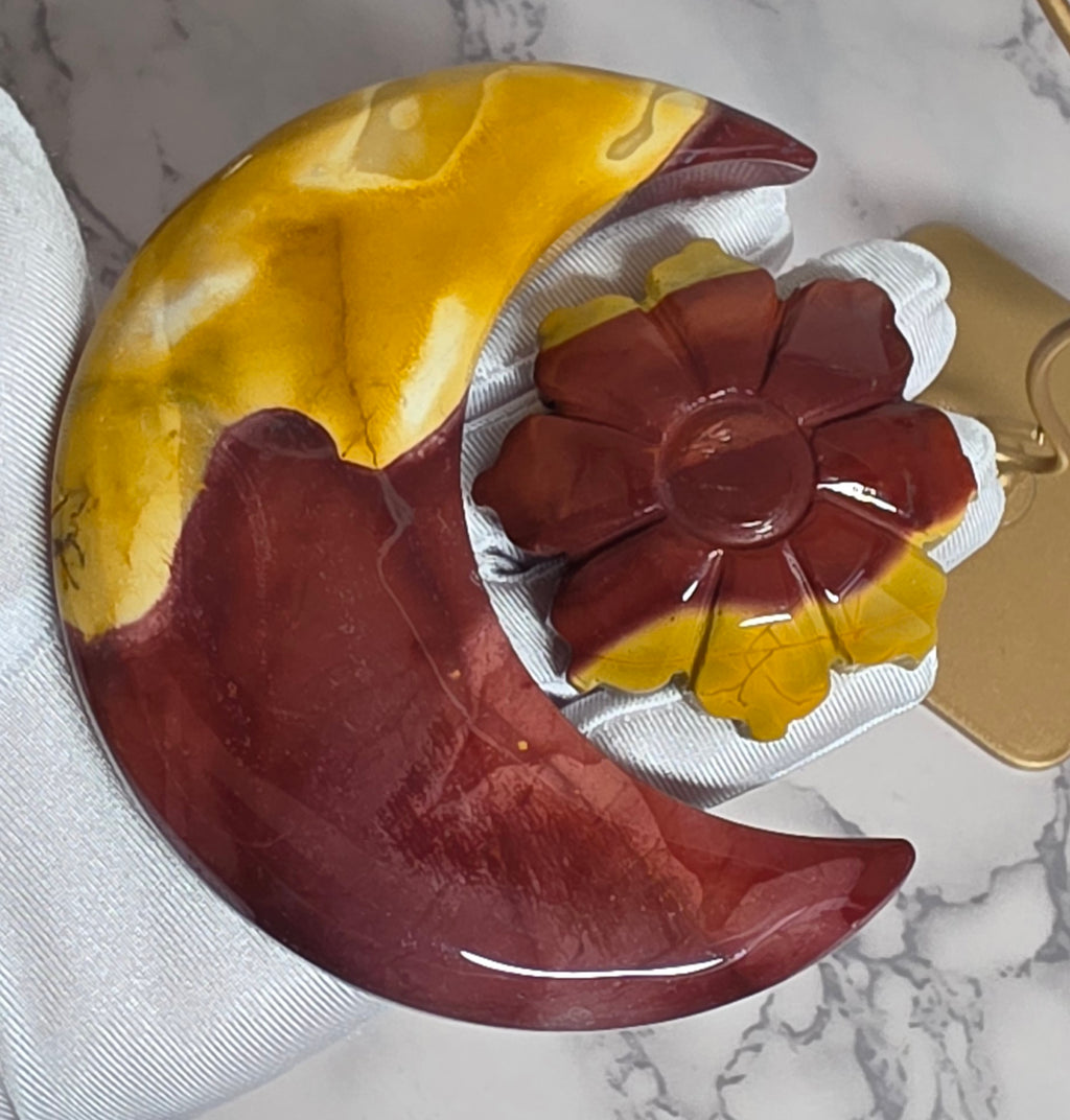 Closeup of polished Mookaite Jasper moon and carved flower in hand
