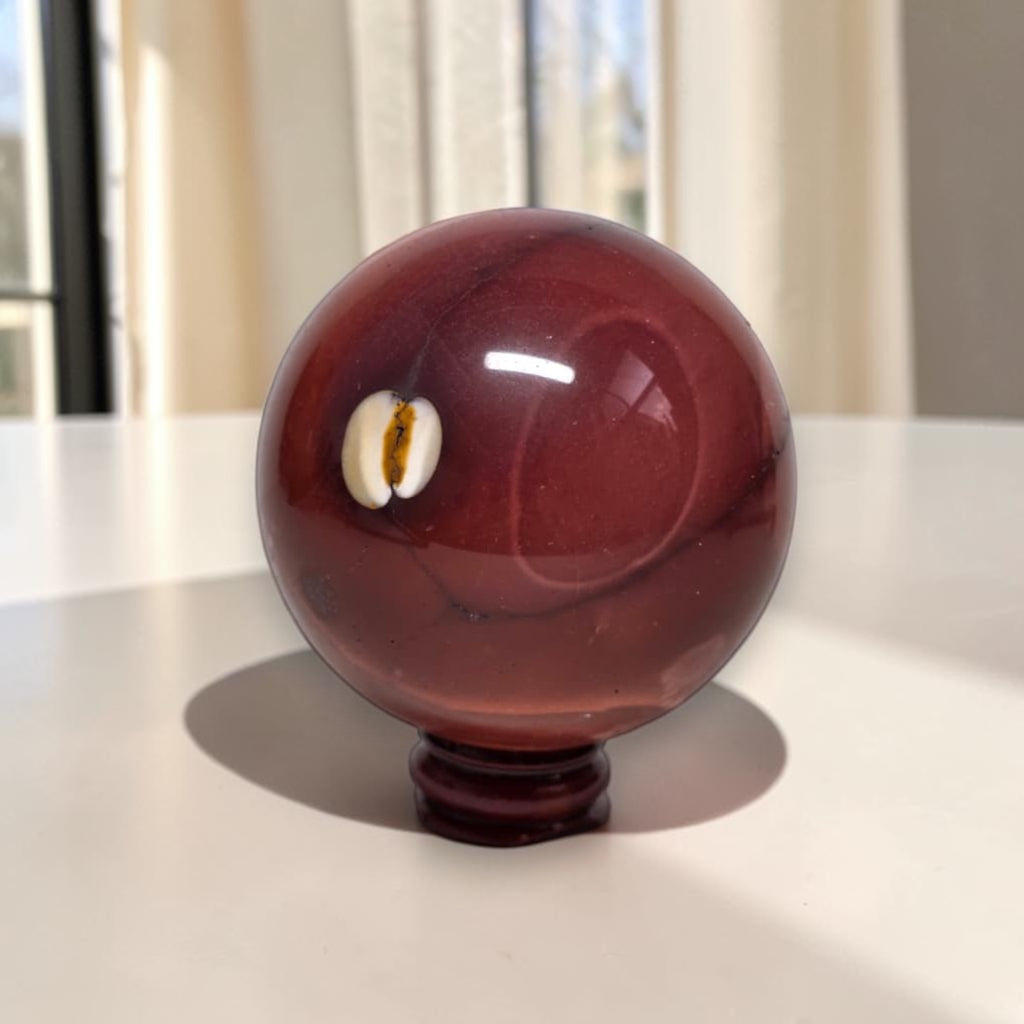 Mookaite jasper sphere, burgundy-red polished gemstone on dark stand, 65mm
