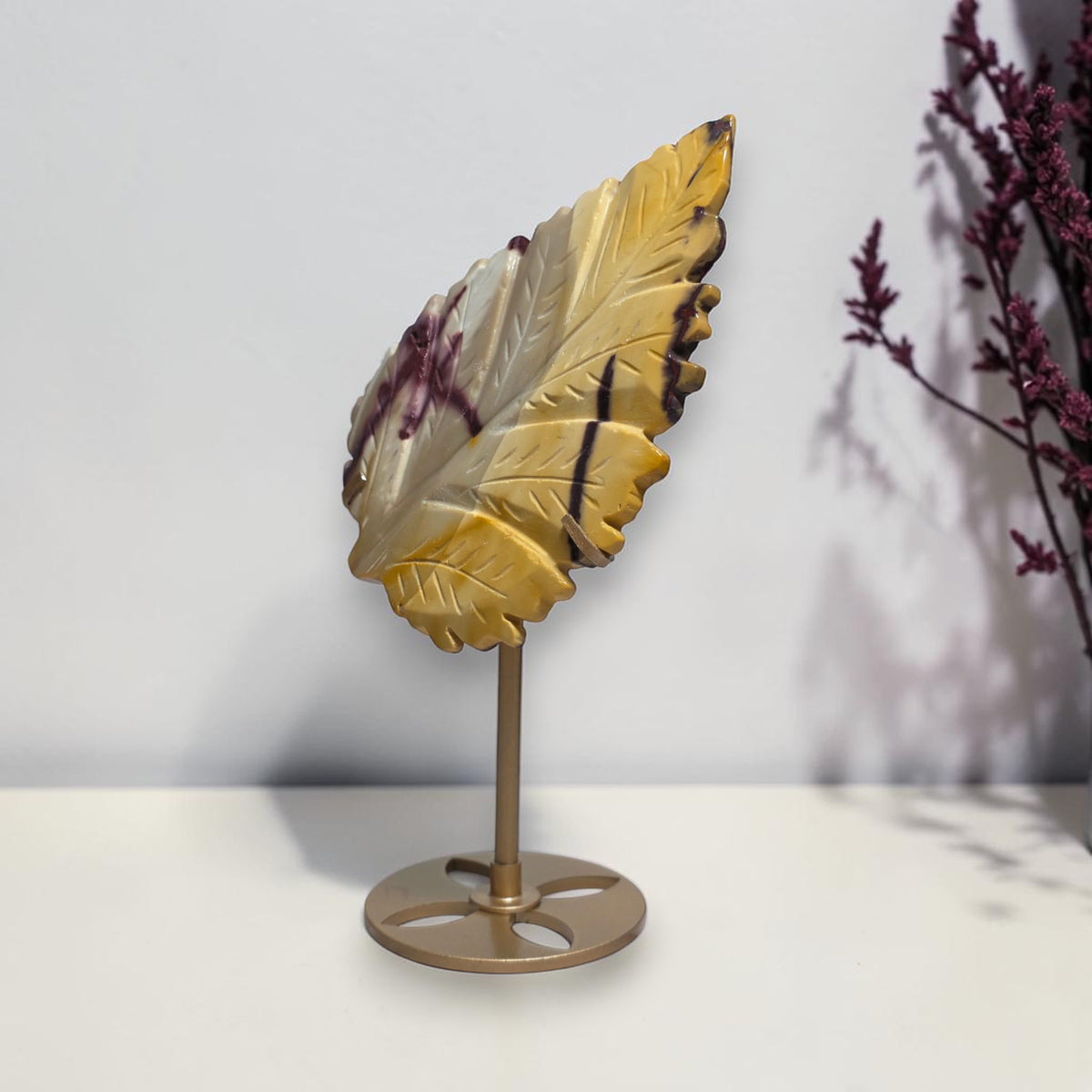 Angled view of yellow Mookaite Jasper leaf carving on stand