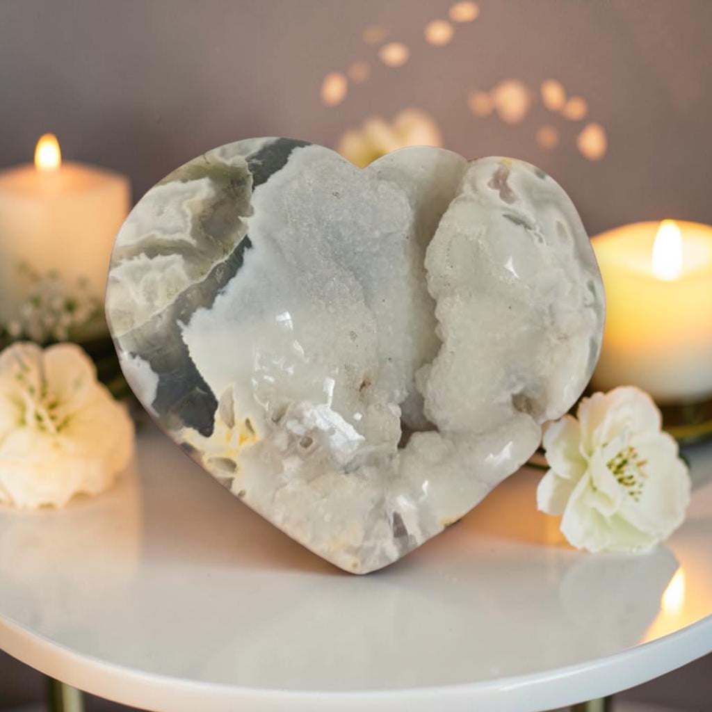 Heart-shaped stone on a table with candles and flowers in the background