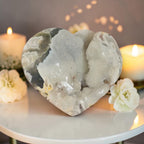 Heart-shaped stone on a table with candles and flowers in the background