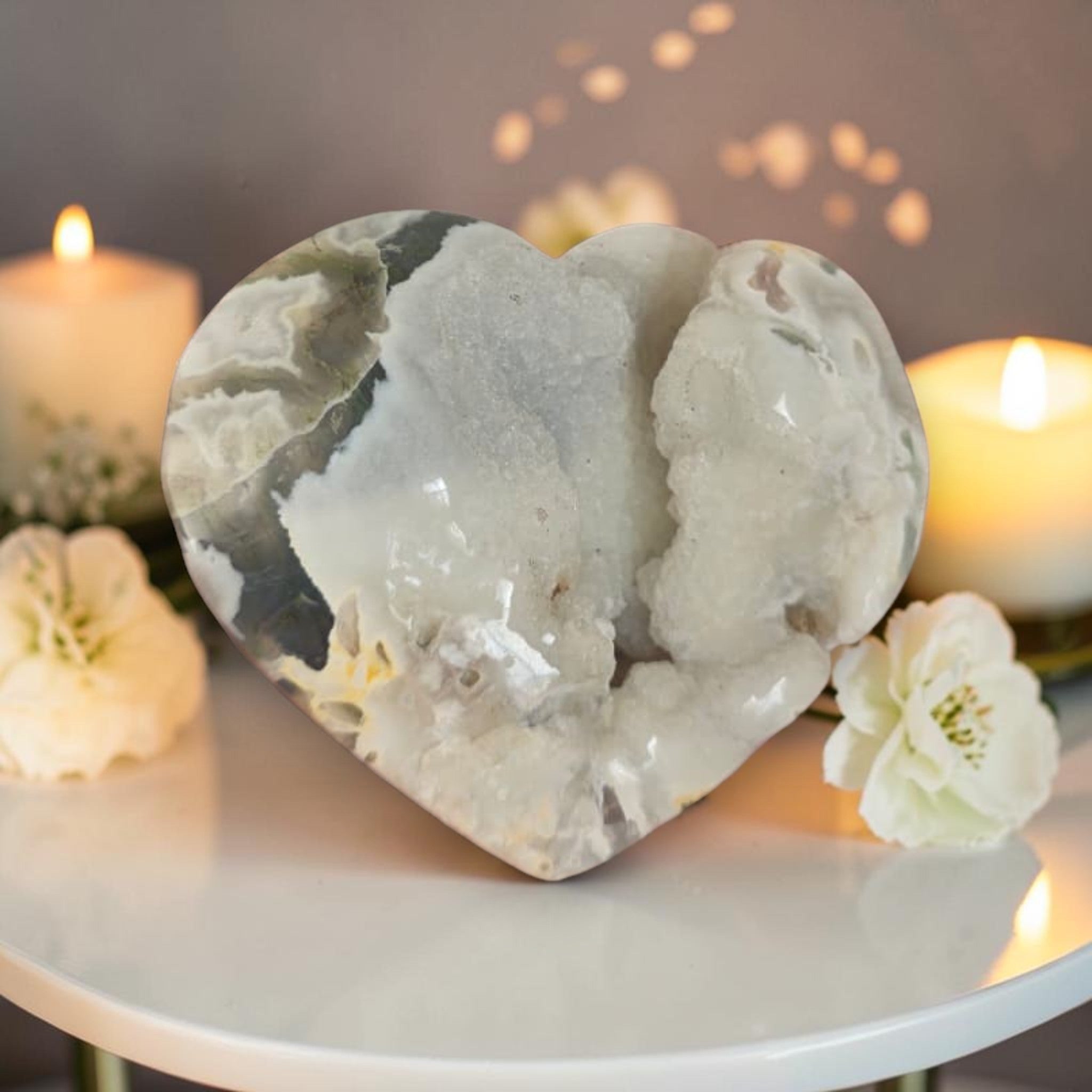 Heart-shaped stone on a table with candles and flowers in the background