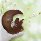 Natural banded agate moon fairy held in gloved hands, close up detail