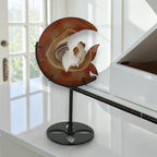 Banded agate moon fairy sculpture on black metal stand, front view with white floral background