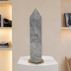 Gray rutilated quartz tower obelisk with dark needle rutiles standing on base