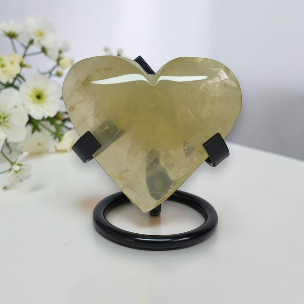 Gold heart-shaped object on a stand with white flowers in the background
