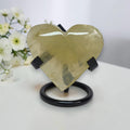 Gold heart-shaped object on a stand with white flowers in the background