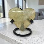 Heart-shaped yellow stone on a black stand in a modern indoor setting
