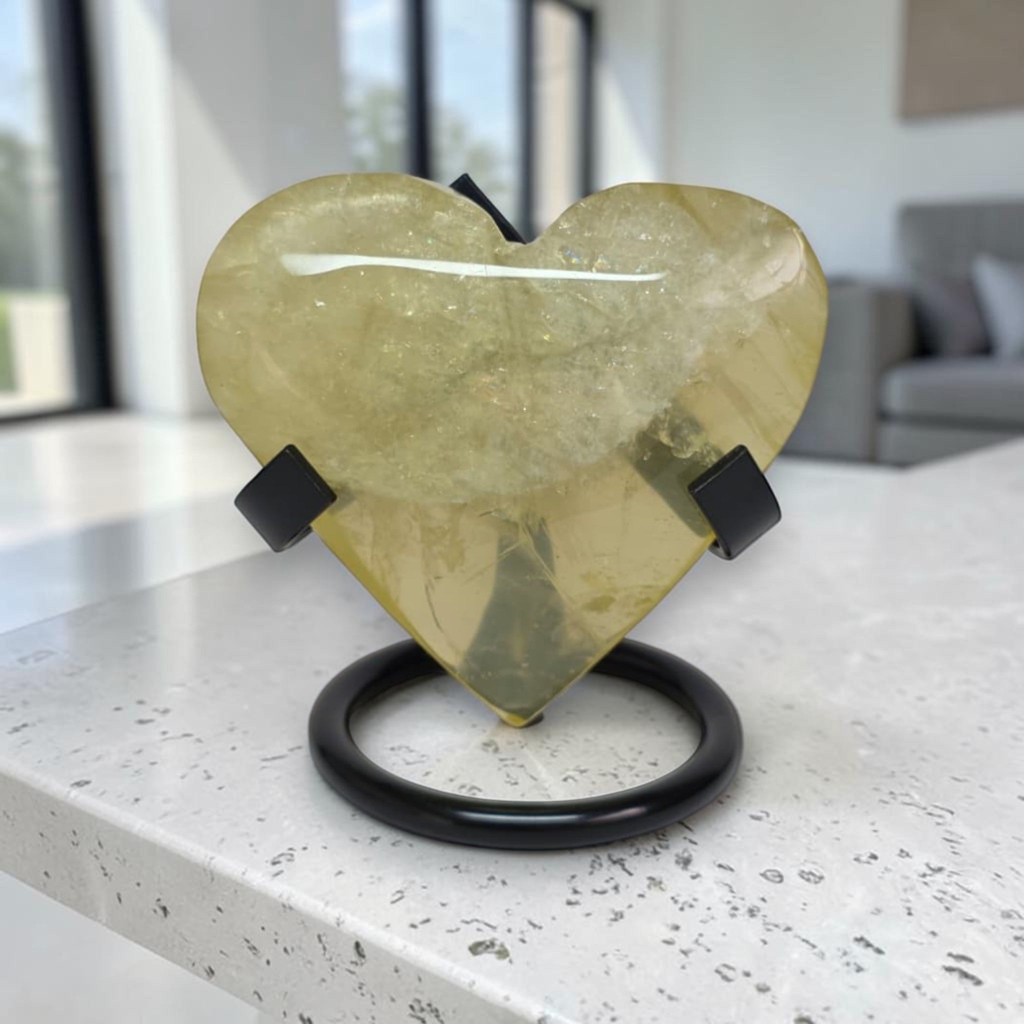 Heart-shaped yellow stone on a black stand in a modern indoor setting