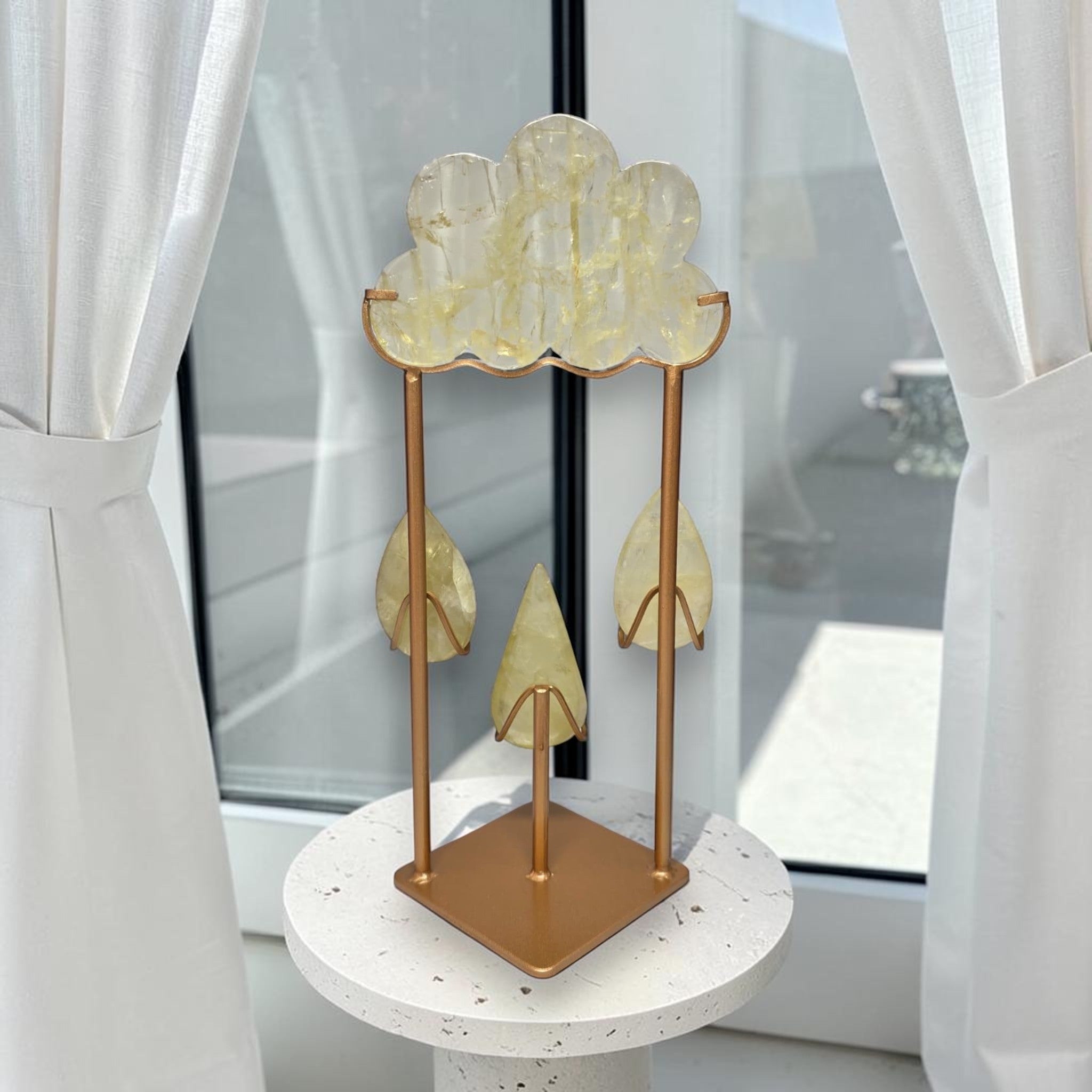Gold-toned crystal cloud sculpture with hanging teardrop pieces on a display stand