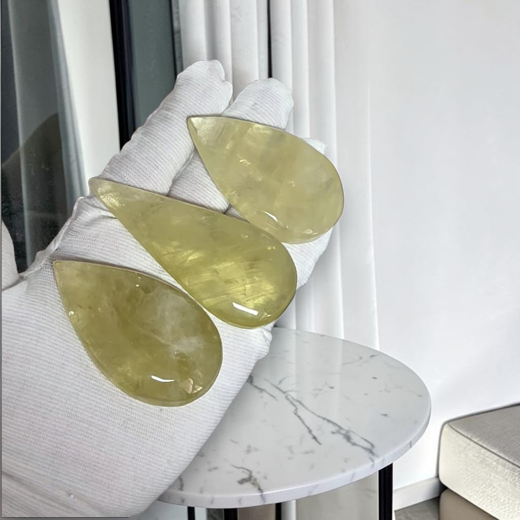 Gloved hand holding three yellow translucent crystal slabs near a round table