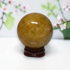 Natural Golden Healer Quartz sphere on wood stand with cherry blossom background