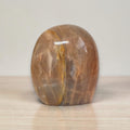 Polished peach-brown freeform crystal palm stone with glossy surface