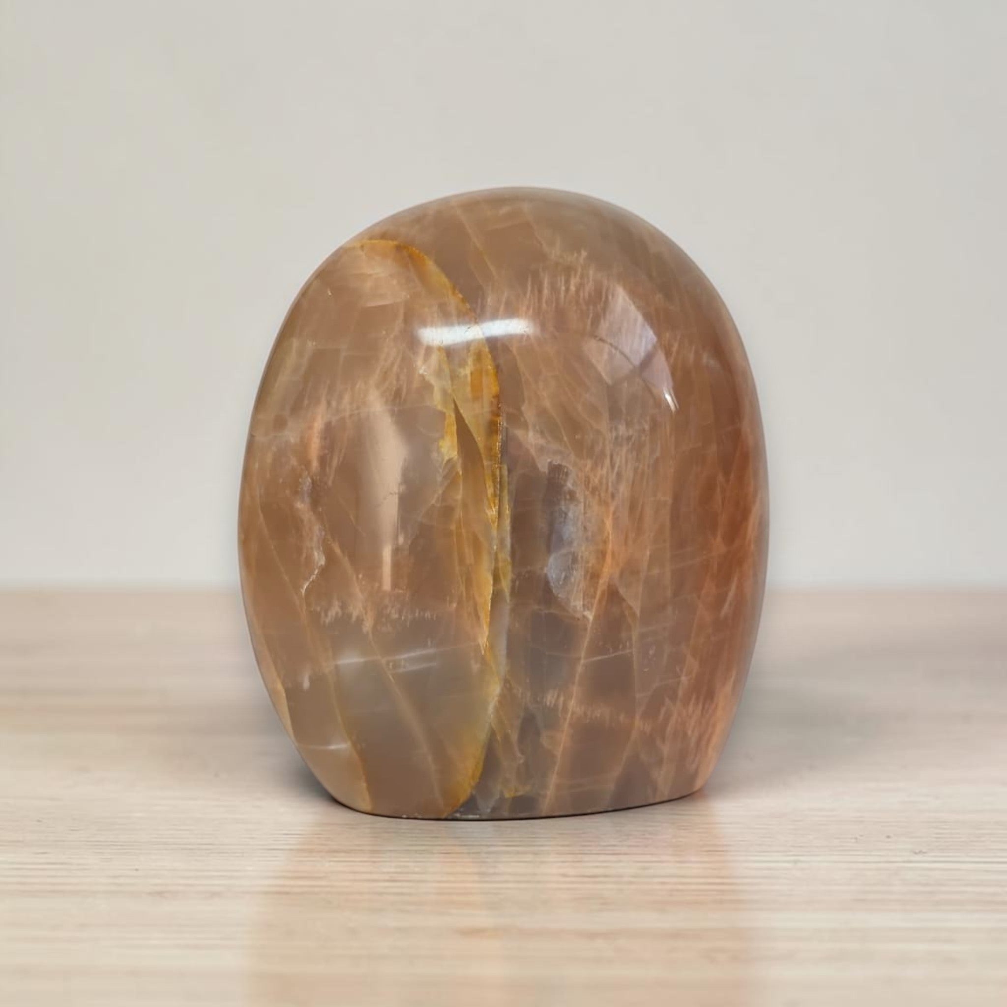 Polished peach-brown freeform crystal palm stone with glossy surface