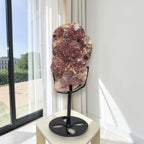 Pink amethyst crystal cluster slab on black stand base, displayed by large window