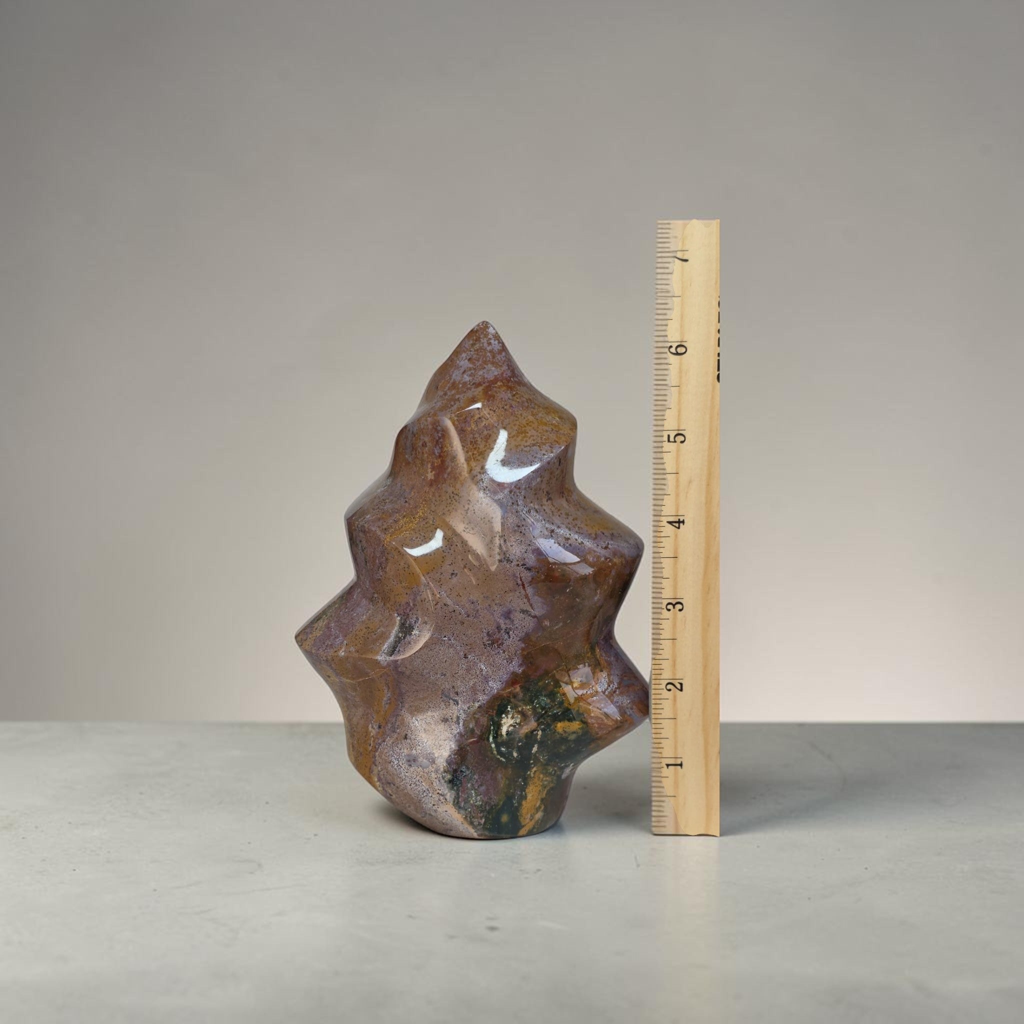 Brown stone sculpture next to a ruler on a gray background