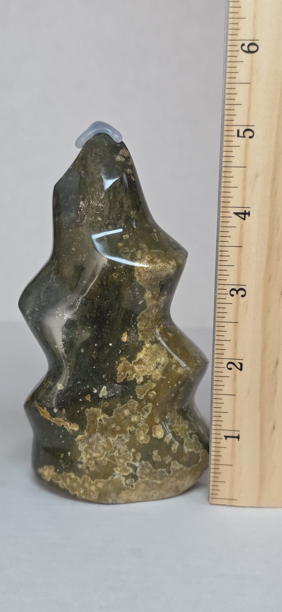 Polished ocean jasper flame-shaped stone in dark green with gold speckles; 5 in