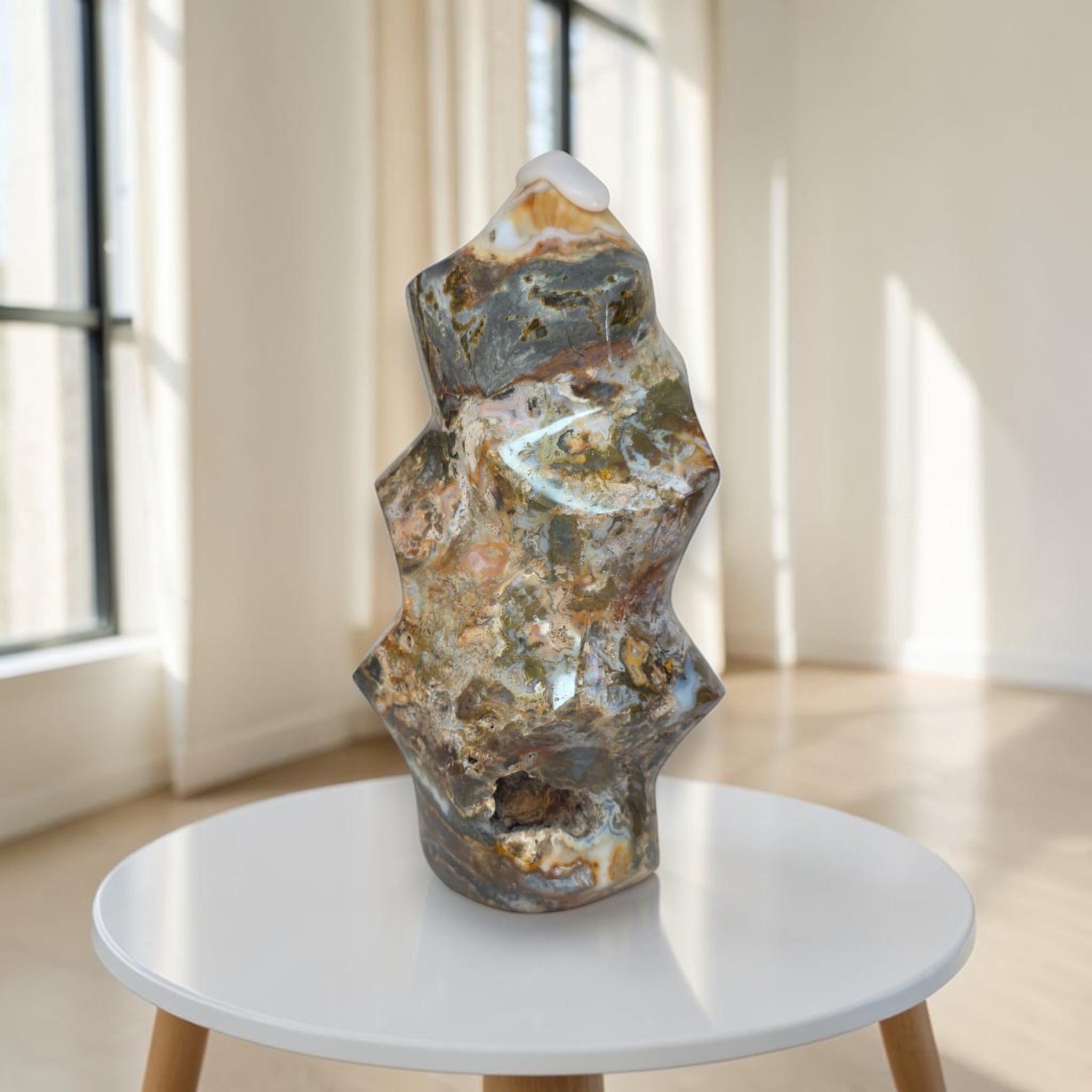 Decorative stone sculpture on a white round table in a bright room with large windows.