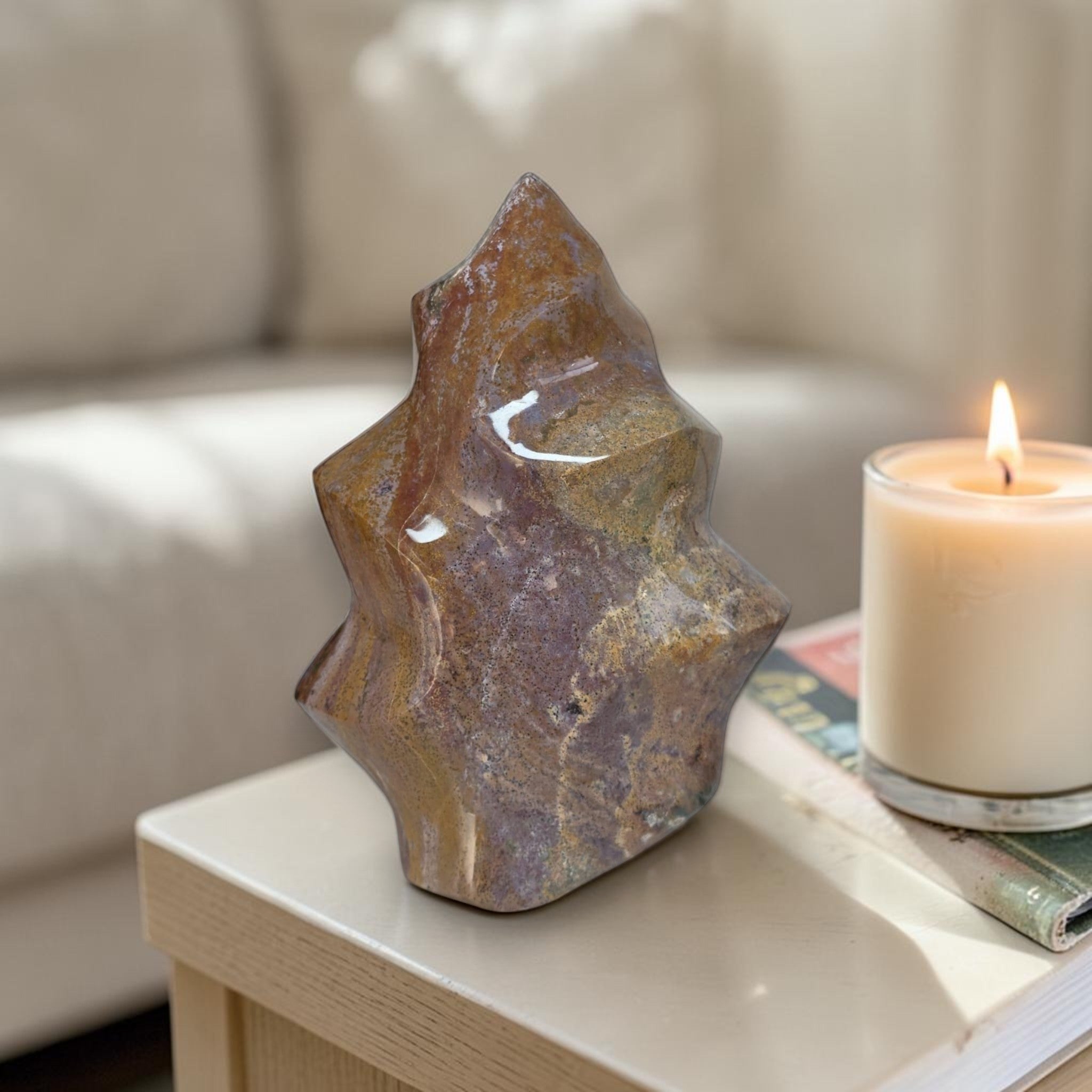 Decorative stone sculpture on a table with a lit candle in the background