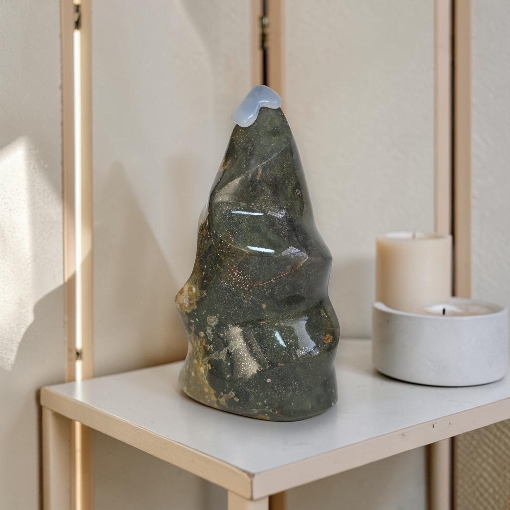 Decorative stone sculpture on a shelf with candles in a softly lit room.