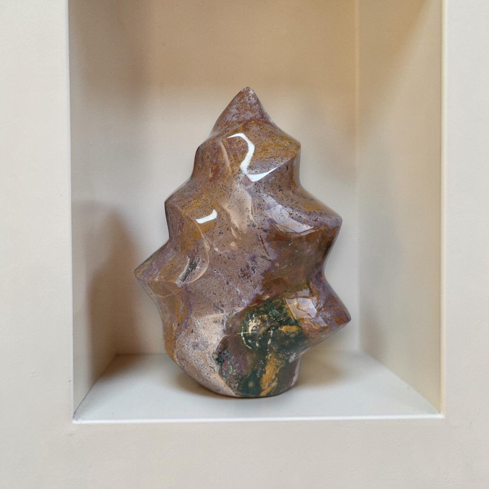 Decorative stone sculpture on a white pedestal against a beige wall