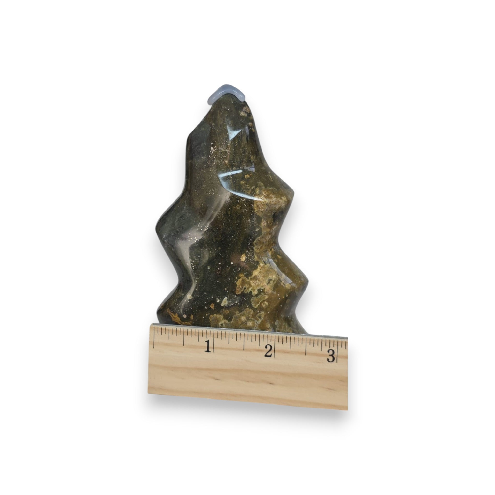 Decorative stone figure with a ruler for scale on a white background