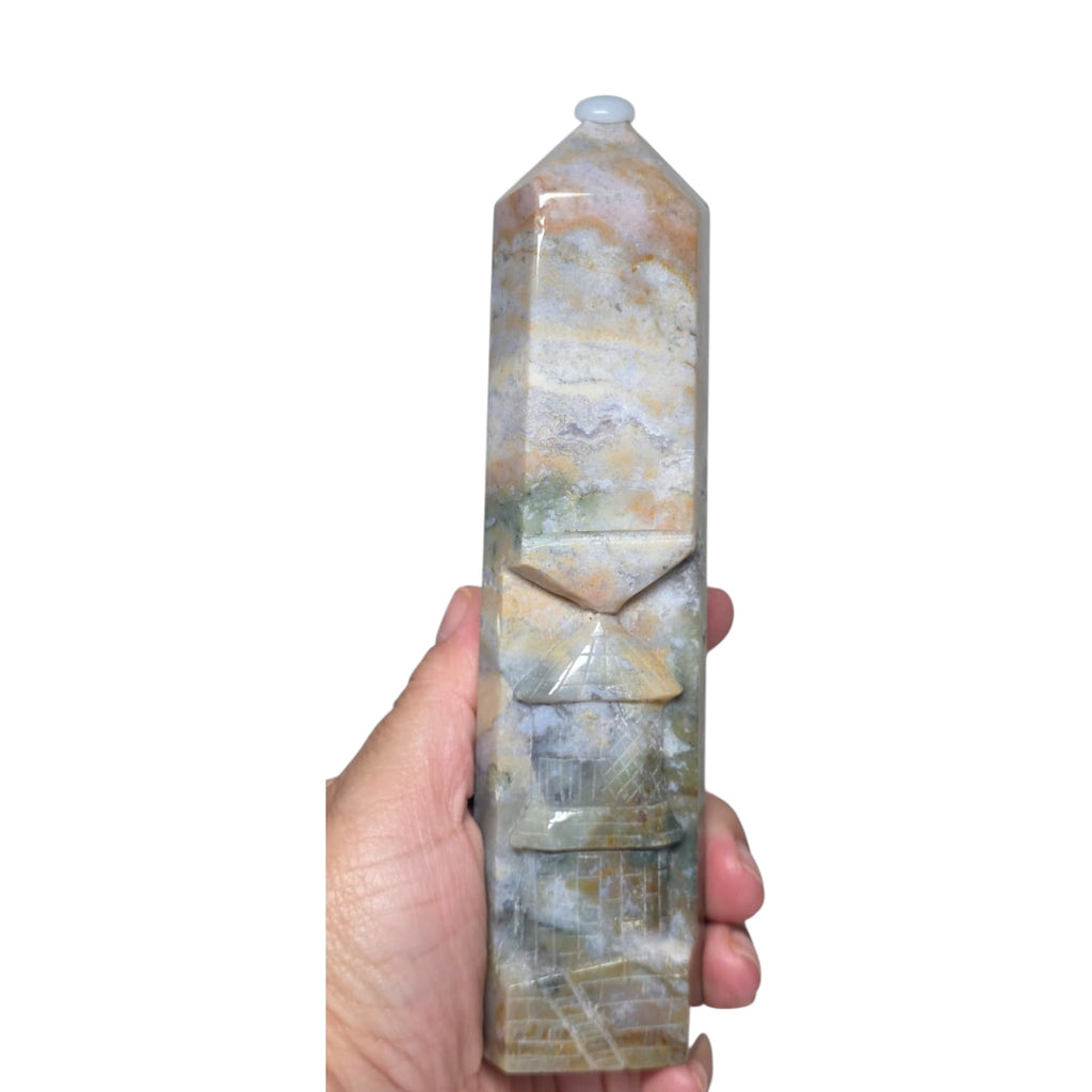 Ocean jasper tower held in hand, carved facets and swirled blue-gray stone