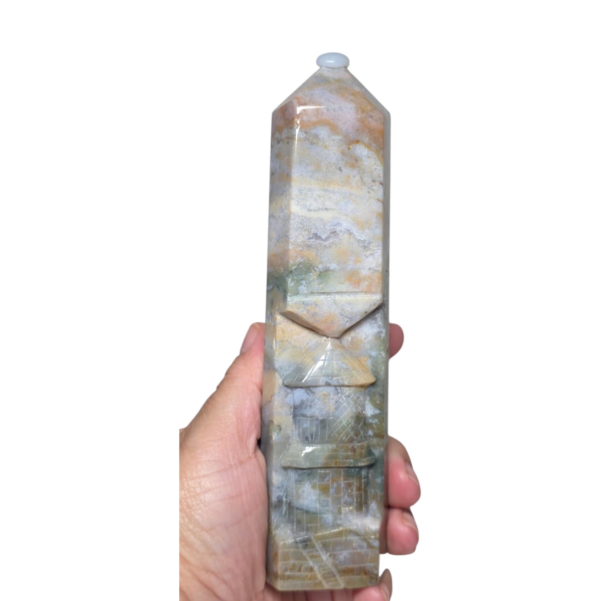 Ocean jasper tower held in hand, carved facets and swirled blue-gray stone